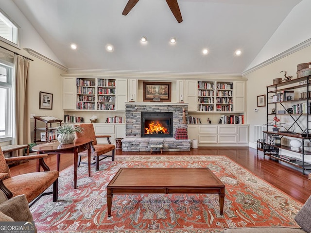 living area featuring light wood-type flooring, a stone fireplace, ornamental molding, ceiling fan, and high vaulted ceiling