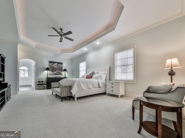 bedroom featuring a tray ceiling, light carpet, ornamental molding, and ceiling fan