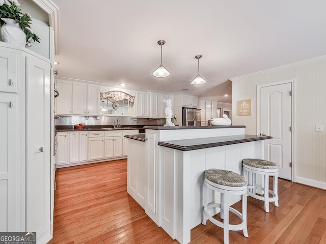 kitchen with a kitchen bar, a center island, white cabinetry, decorative light fixtures, and stainless steel fridge with ice dispenser