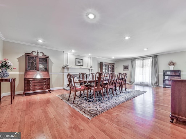 dining room with light wood-type flooring and crown molding