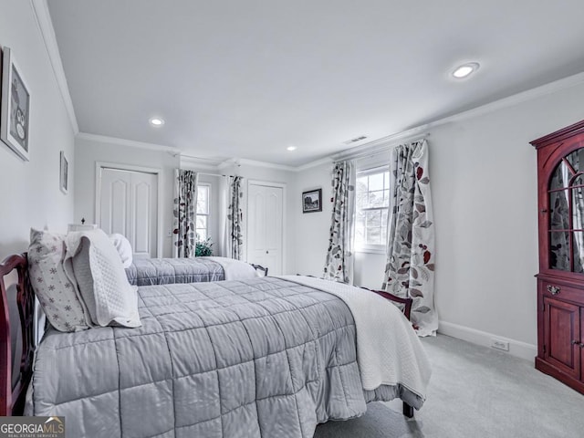 bedroom featuring ornamental molding, multiple closets, and light carpet