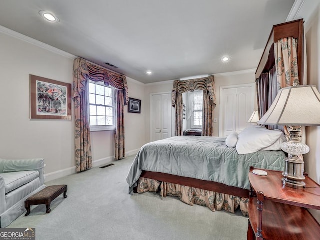 bedroom with ornamental molding, light colored carpet, and multiple closets