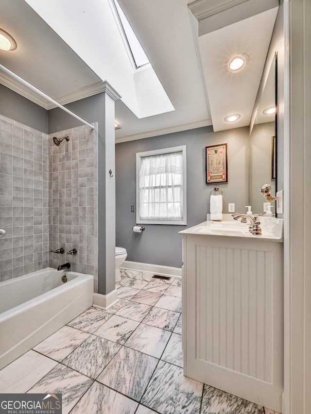 full bathroom featuring toilet, tiled shower / bath, a skylight, crown molding, and vanity