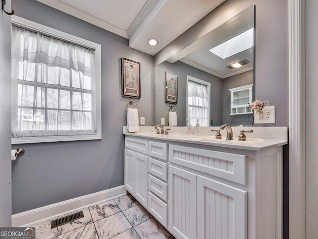 bathroom with a skylight, vanity, and ornamental molding