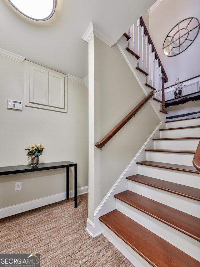 staircase featuring ornamental molding and hardwood / wood-style floors