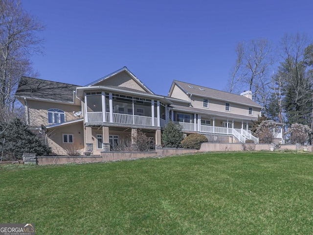 rear view of house featuring a lawn, a sunroom, and covered porch