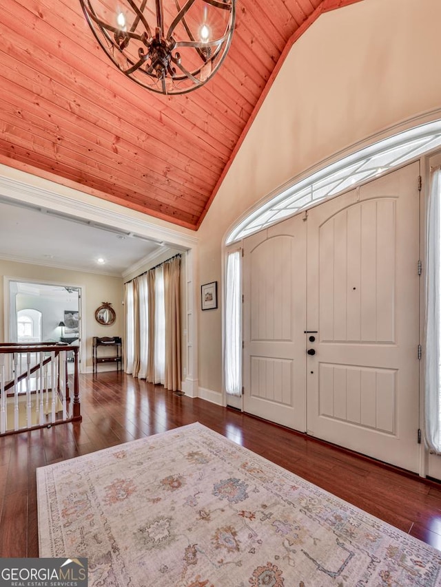 foyer entrance with a notable chandelier, crown molding, dark wood-type flooring, wooden ceiling, and high vaulted ceiling