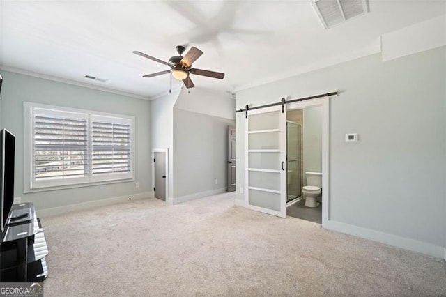 unfurnished bedroom featuring connected bathroom, ceiling fan, crown molding, a barn door, and light colored carpet