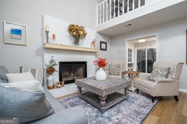 living room featuring wood-type flooring and a stone fireplace