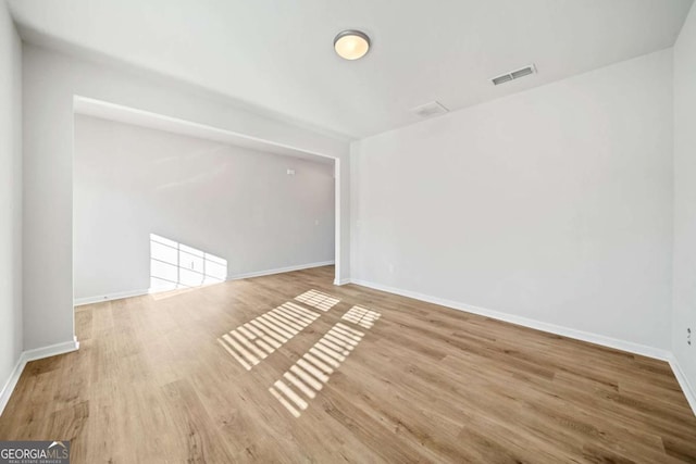 unfurnished room with light wood-type flooring, visible vents, and baseboards