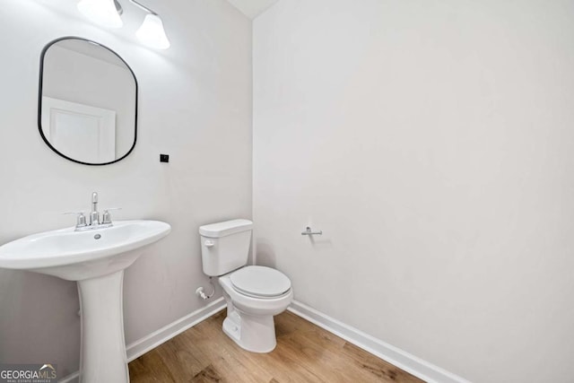 bathroom with wood finished floors, toilet, and baseboards