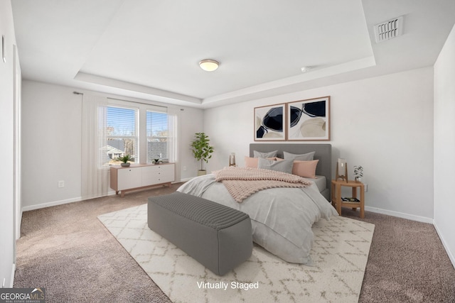 carpeted bedroom featuring visible vents, a tray ceiling, and baseboards