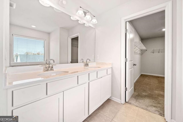 bathroom with tile patterned flooring, a sink, a spacious closet, and double vanity