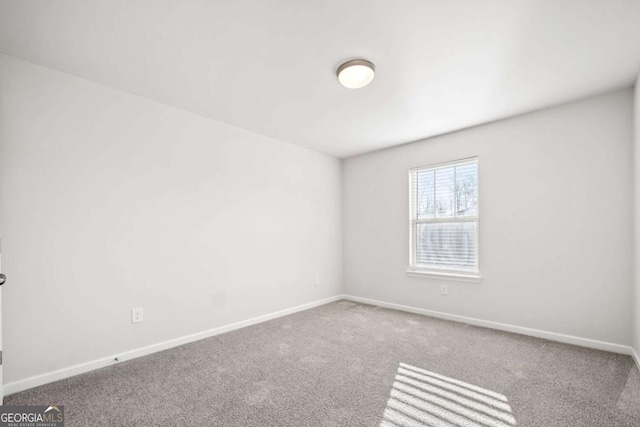 carpeted spare room featuring baseboards