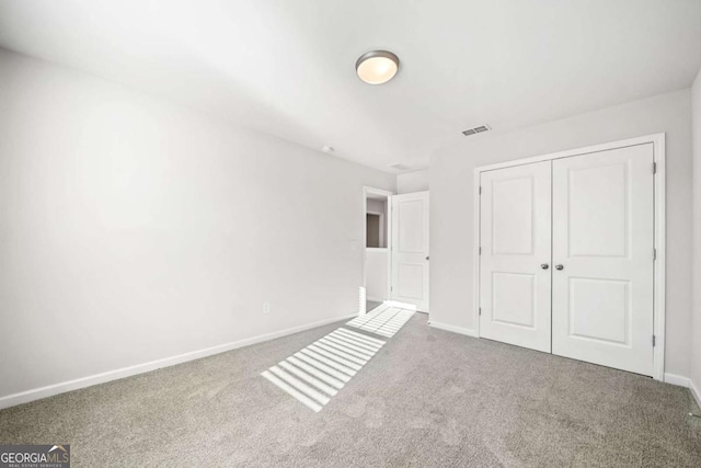 unfurnished bedroom featuring carpet floors, a closet, visible vents, and baseboards