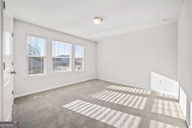 carpeted spare room with visible vents and baseboards