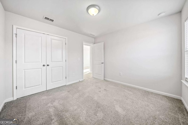 unfurnished bedroom featuring carpet floors, baseboards, visible vents, and a closet