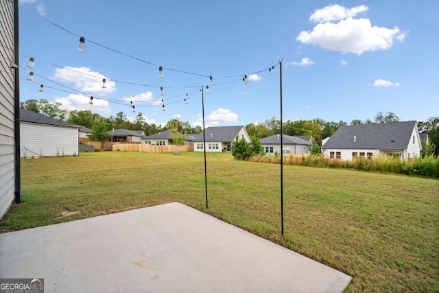 view of yard featuring a patio area, fence, and a residential view