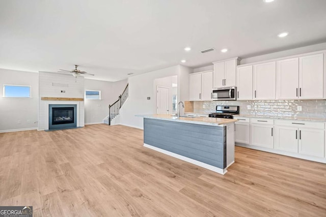 kitchen with white cabinetry, stainless steel appliances, a sink, and open floor plan