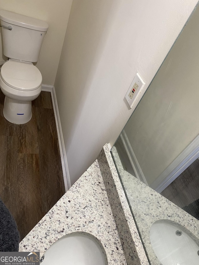 bathroom with baseboards, toilet, wood finished floors, and vanity