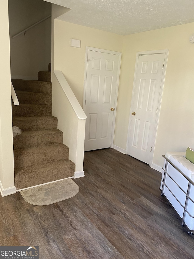 staircase featuring baseboards, a textured ceiling, and wood finished floors