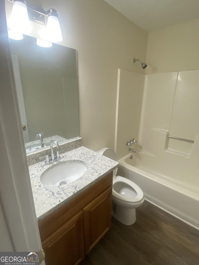 bathroom featuring washtub / shower combination, toilet, wood finished floors, and vanity