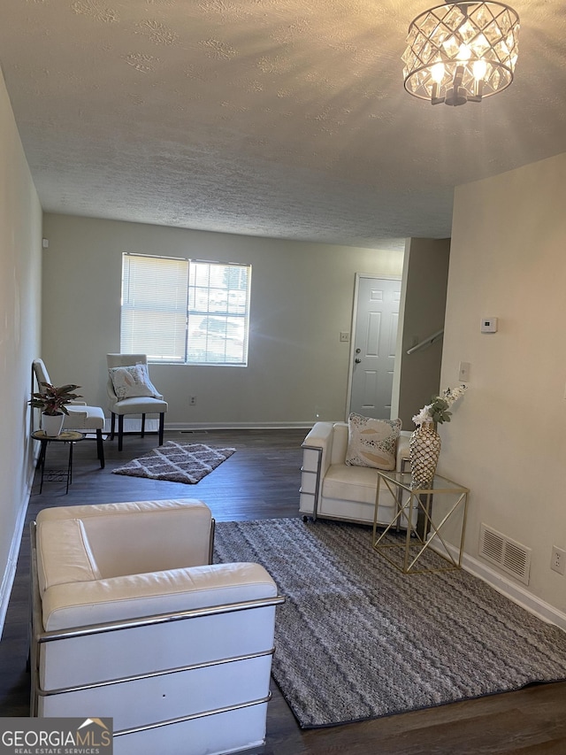 living area with visible vents, a textured ceiling, baseboards, and wood finished floors