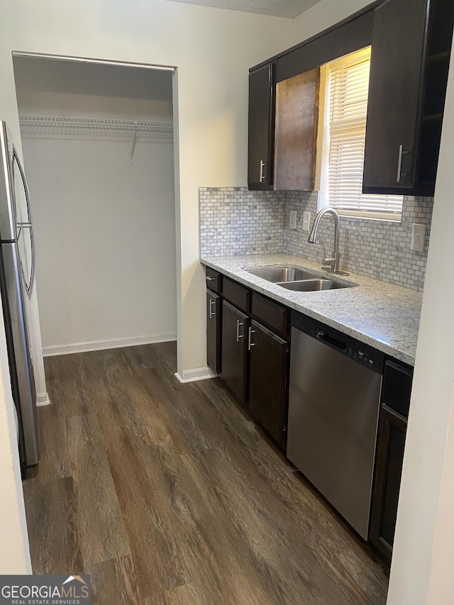 kitchen featuring a sink, dark wood-style floors, stainless steel appliances, decorative backsplash, and baseboards