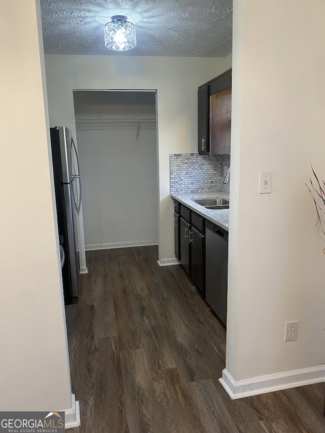 kitchen featuring dark wood-style flooring, a sink, light countertops, appliances with stainless steel finishes, and backsplash