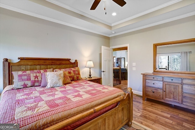 bedroom with light hardwood / wood-style flooring, ornamental molding, a tray ceiling, stainless steel fridge, and ceiling fan