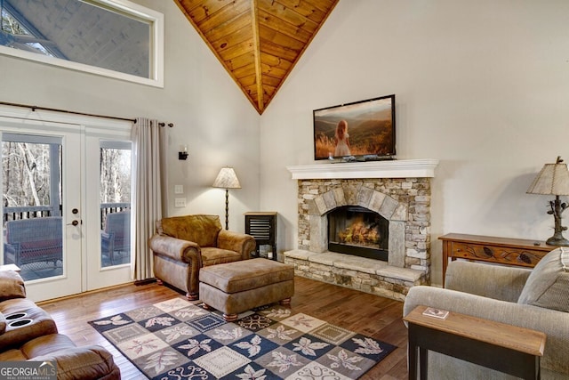 living room with french doors, wood ceiling, wood-type flooring, and a stone fireplace