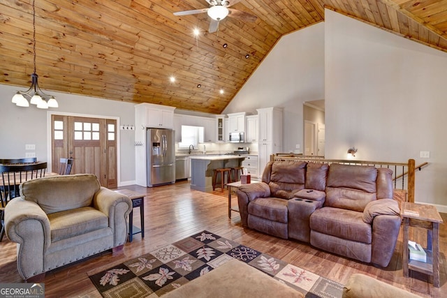 living room with wood ceiling, light hardwood / wood-style flooring, high vaulted ceiling, and ceiling fan with notable chandelier