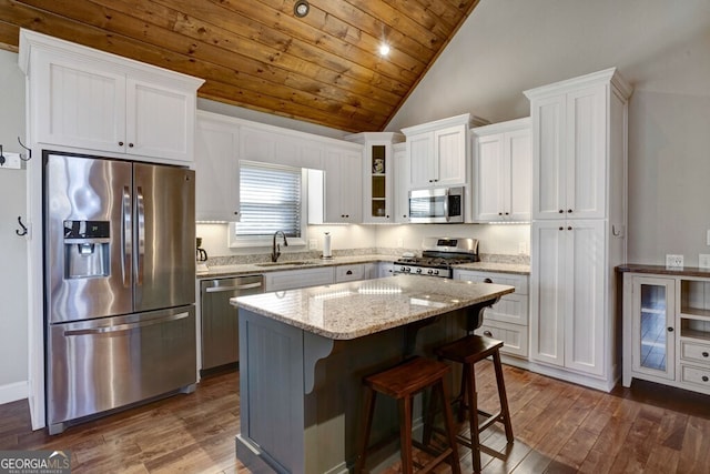 kitchen with appliances with stainless steel finishes, sink, a breakfast bar area, white cabinets, and a center island