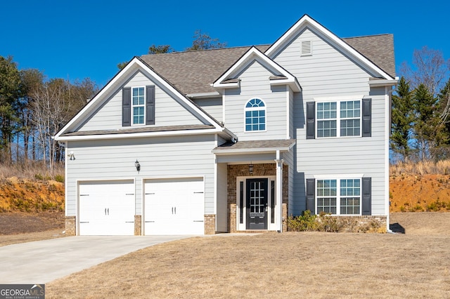 traditional home featuring a shingled roof, a front yard, stone siding, and driveway