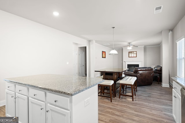 kitchen with pendant lighting, white cabinets, a glass covered fireplace, and a center island