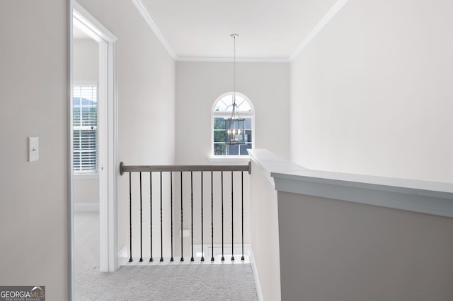 hall featuring a healthy amount of sunlight, crown molding, carpet flooring, and an upstairs landing