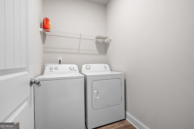 washroom featuring washer and dryer, laundry area, baseboards, and wood finished floors