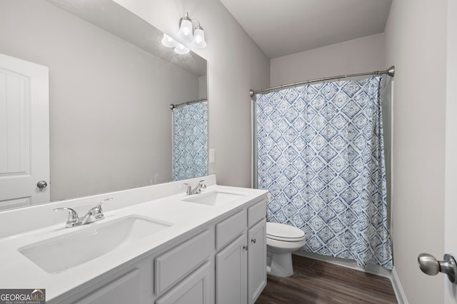 full bath with wood finished floors, a sink, toilet, and double vanity