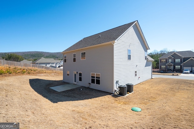 view of side of home with central AC, fence, and a residential view