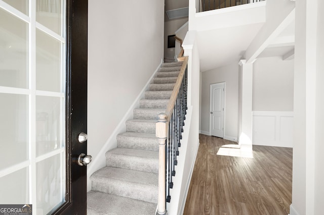 staircase featuring wainscoting, wood finished floors, and a decorative wall