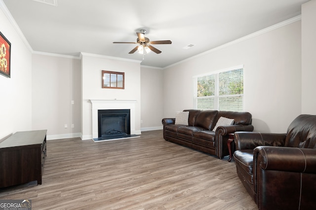 living area with ornamental molding, light wood finished floors, visible vents, and baseboards