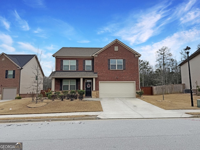 traditional home featuring an attached garage, fence, concrete driveway, and brick siding