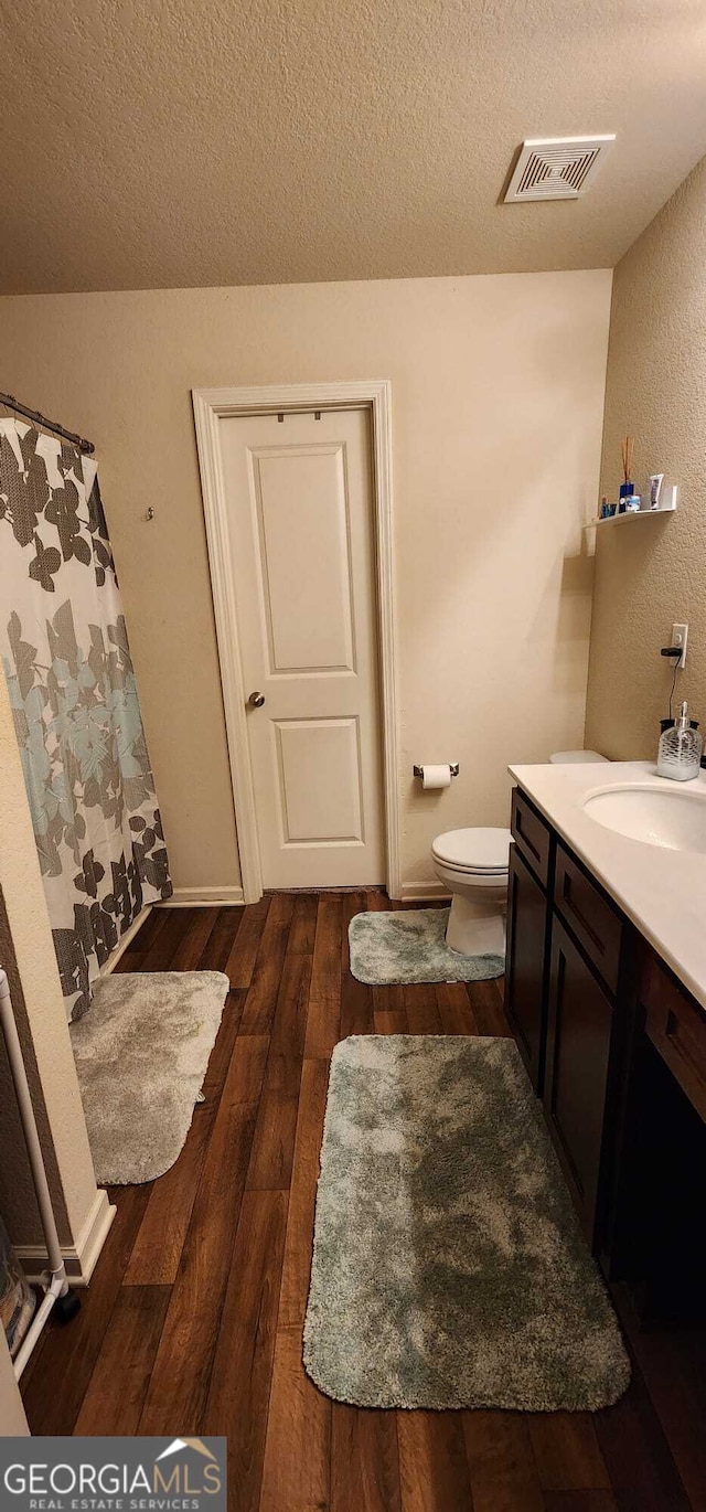 bathroom with vanity, hardwood / wood-style floors, toilet, and a textured ceiling