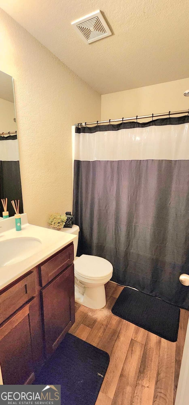 bathroom with hardwood / wood-style flooring, vanity, toilet, and a textured ceiling