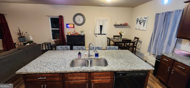 kitchen with an island with sink, dishwasher, sink, and light stone countertops