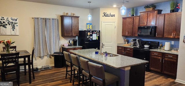 kitchen with sink, dark hardwood / wood-style floors, black appliances, a center island with sink, and decorative light fixtures