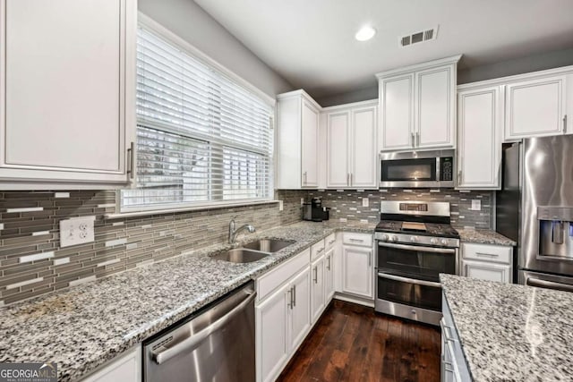 kitchen with sink, stainless steel appliances, white cabinets, dark hardwood / wood-style flooring, and decorative backsplash