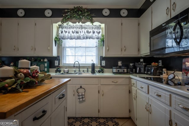 kitchen featuring white cabinetry, sink, ornamental molding, and black appliances