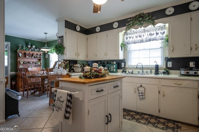 kitchen with white cabinets, butcher block counters, and a sink