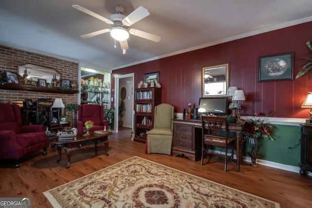 interior space featuring ceiling fan, hardwood / wood-style floors, ornamental molding, brick wall, and a wood stove